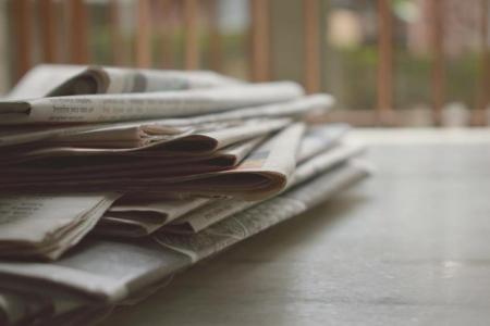 A stack of newspapers on a desk.