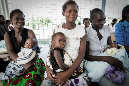 Women and their children in the waiting area at Bondo Subdistrict Hospital in Kenya. Photo of women and their children in Kenya.