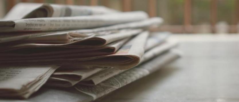 A stack of newspapers on a desk.